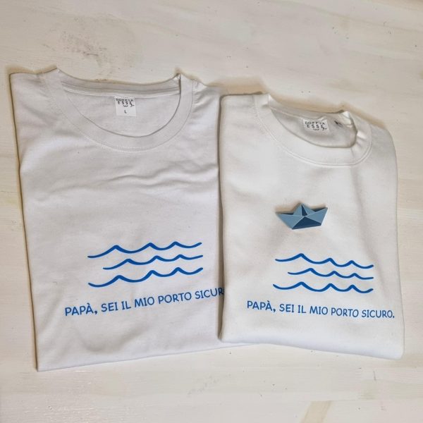 T-shirt e Felpa "Papà sei il mio porto sicuro" con spilla in legno artigianale Un regalo originale e pieno di significato per il tuo papà: t-shirt e felpa personalizzate con la frase "Papà sei il mio porto sicuro" e una spilla in legno a forma di barca, realizzata a mano. Perfette per la Festa del Papà, compleanni o qualsiasi occasione speciale, sono un modo unico per dire "grazie" a chi è sempre stato il tuo punto fermo. Qualità, creatività e tanto amore in un solo prodotto. Scopri tutte le taglie e i colori disponibili e sorprendi tuo papà con un dono unico! Tag utili felpa papà, t-shirt papà, idea regalo festa del papà, regalo originale papà, t-shirt personalizzata papà, felpa personalizzata papà, spilla barca legno, regalo emozionante papà