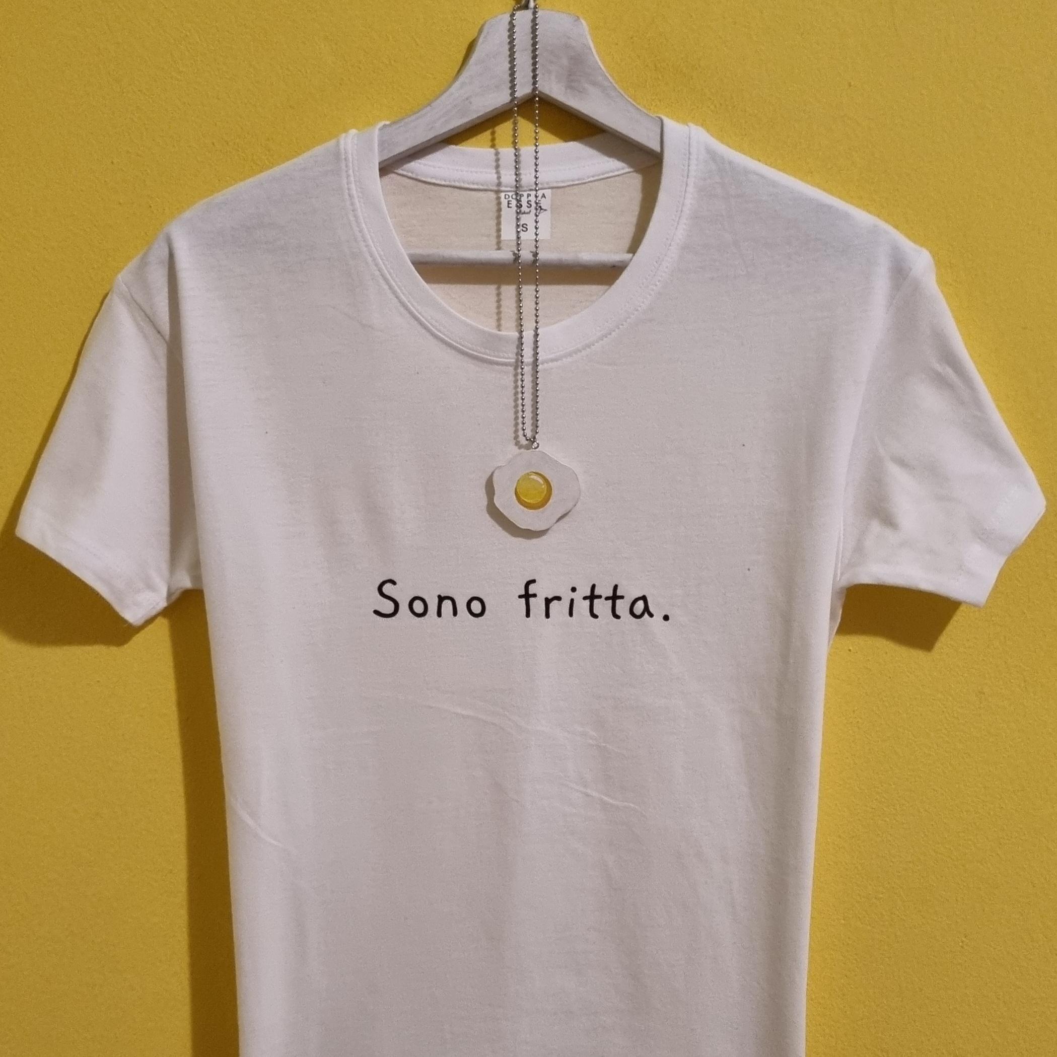 La maglietta perfetta per chi ha la testa… a padella! La t-shirt “Sono frittə” è realizzata in cotone morbido e arriva con una collanina adorabile a forma di uovo al tegamino: un mix irresistibile di ironia, stile e autoironia. Ideale per chi ama ridere, per chi è sempre di corsa o per chi vuole un look leggero e super originale. Un’idea regalo divertente e un capo unico nella tua collezione food-style. Caratteristiche: Cotone morbido Stampa ironica Collanina uovo inclusa Idea regalo perfetta Sceglila se oggi… ti senti fritta. 😄🍳